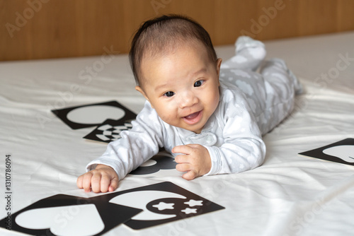5 month old baby playing with picture cards on the bed in the morning.