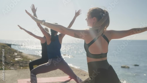 Wallpaper Mural Athletic women practicing warrior two yoga pose on sandy beach during sunny morning, demonstrating strength, balance, and harmony near ocean coastline Torontodigital.ca