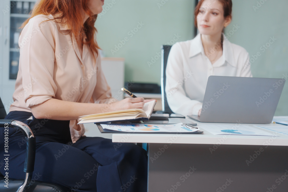 Two Caucasian women work in an office, happily using laptops and computers at a desk, discussing financial projects, analyzing financial statements,collaborating in a meeting to ensure effective Two Caucasian women work in an office, happily using laptops and computers at a desk, discussing financial projects, analyzing financial statements,collaborating in a meeting to ensure effective
