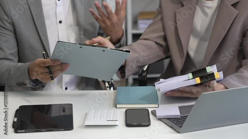 Two Asian businessmen sit in the office using laptops. They manage business tasks, communicate with clients, analyze data, and oversee projects to ensure success and efficiency in their operations