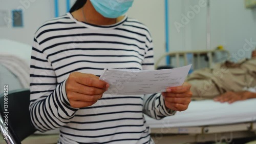 A daughter sits by her elderly father's hospital bedside, caring for him, giving him medicine, holding his hand and encouraging him as he struggles with the stress of his treatment and medical bills