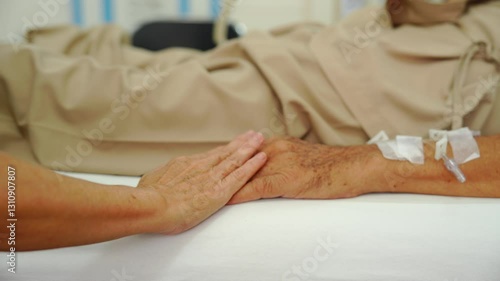 A daughter sits by her elderly father's hospital bedside, caring for him, giving him medicine, holding his hand and encouraging him as he struggles with the stress of his treatment and medical bills