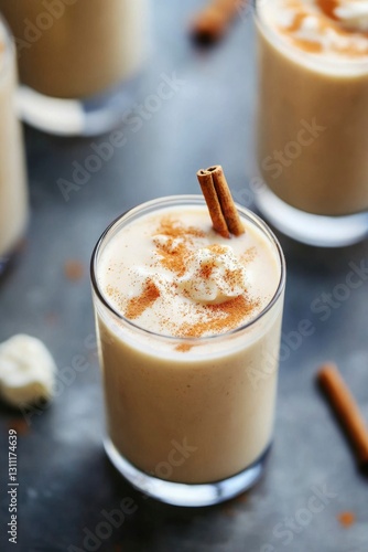 Creamy spiced drink with cinnamon sticks on dark background