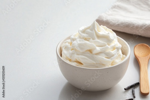 Creamy whipped topping swirled in bowl, accompanied by wooden sp