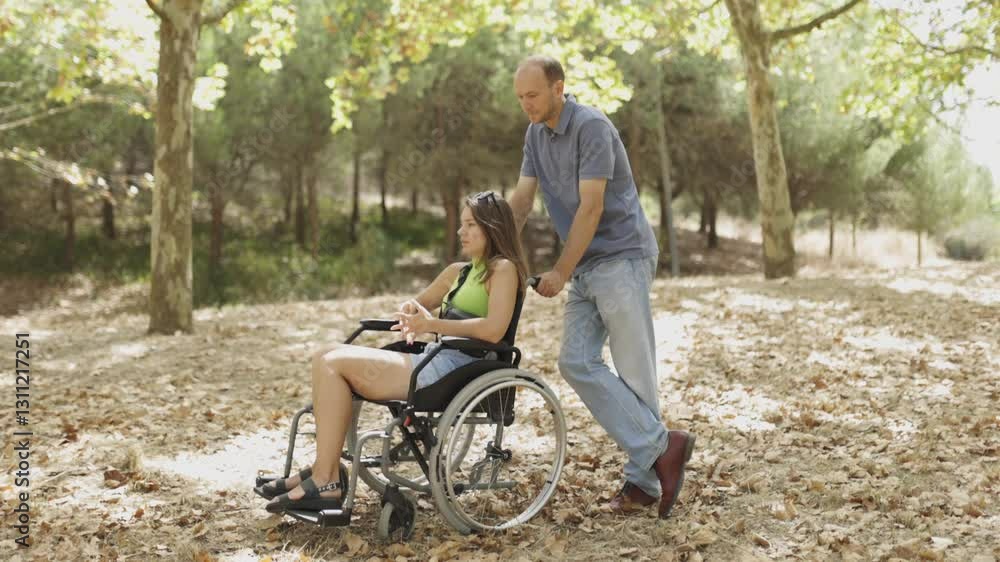 Man pushing woman in wheelchair through forest Man pushing woman in wheelchair through forest