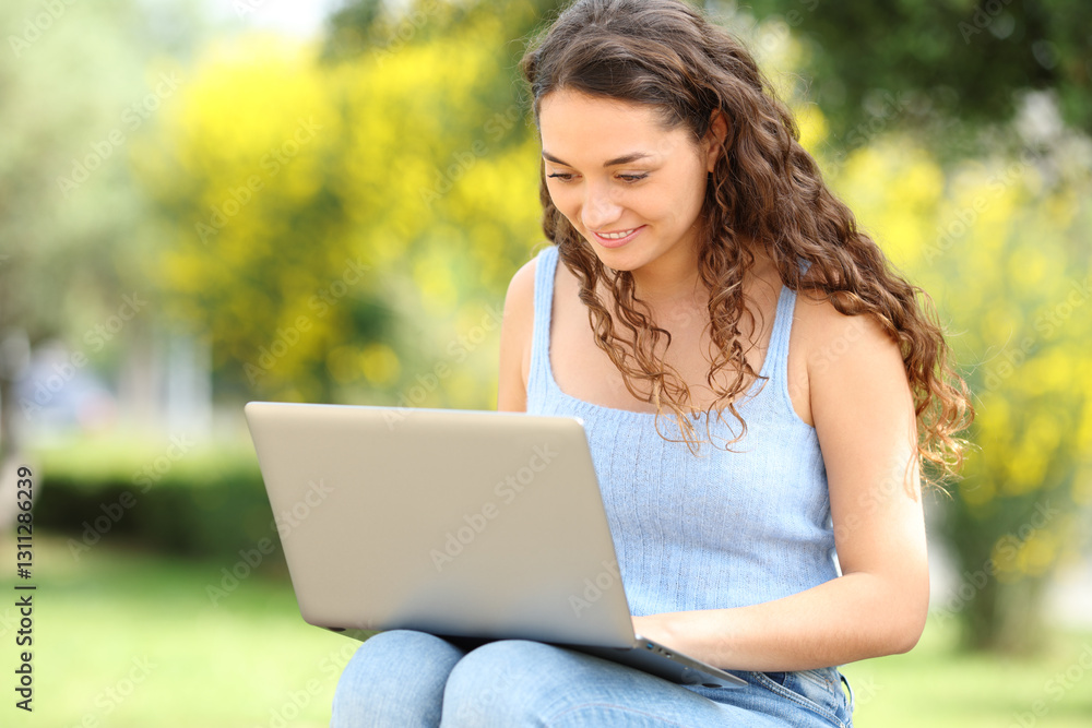 Happy woman typing on laptop in a park Happy woman typing on laptop in a park