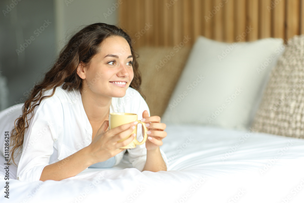 Happy woman on a bed drinking coffee looking away Happy woman on a bed drinking coffee looking away