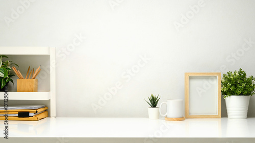 Fototapeta Naklejka Na Ścianę i Meble -  Minimalist workspace with small shelf, picture frame, cup of coffee and supplies