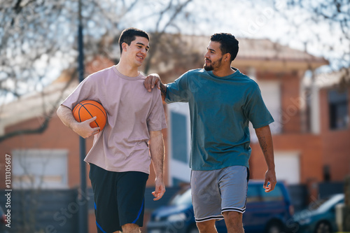 Two male friends walking and talking after playing basketball outdoors