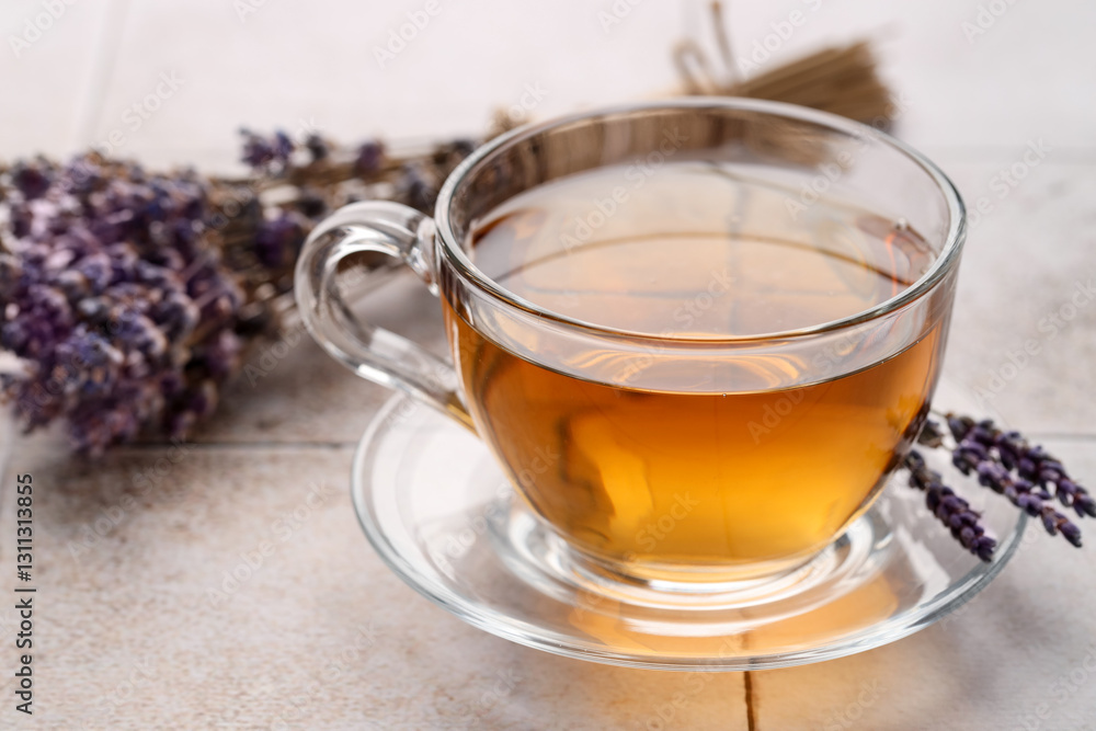 Aromatic lavender tea in glass cup and dry flowers on white tiled table, closeup Aromatic lavender tea in glass cup and dry flowers on white tiled table, closeup
