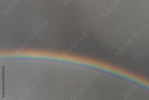 Vibrant colorful rainbow arcing against a dark dramatic stormy sky