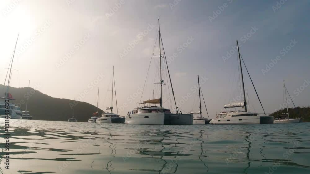 Catamarans and yachts on the water during golden hour sunset Catamarans and yachts on the water during golden hour sunset
