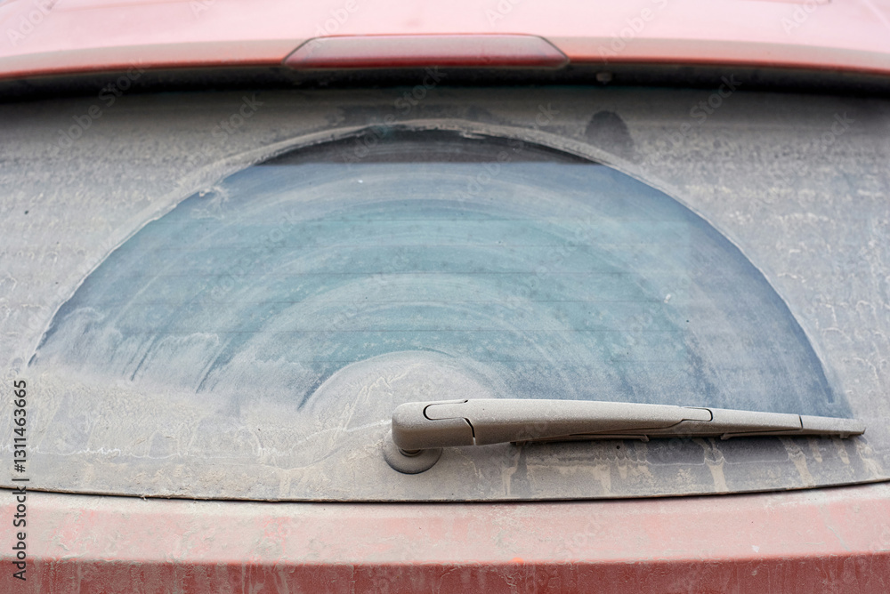 Close-up of car wiper blade and windshield covered in dust with wiper blade cleaning pattern, need for routine maintenance to ensure road safety and clear vision..