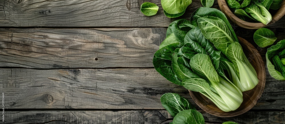 Fototapeta premium Fresh bok choy arranged in wooden bowls on a rustic wooden table with textured gray planks creating ample copy space on the right side