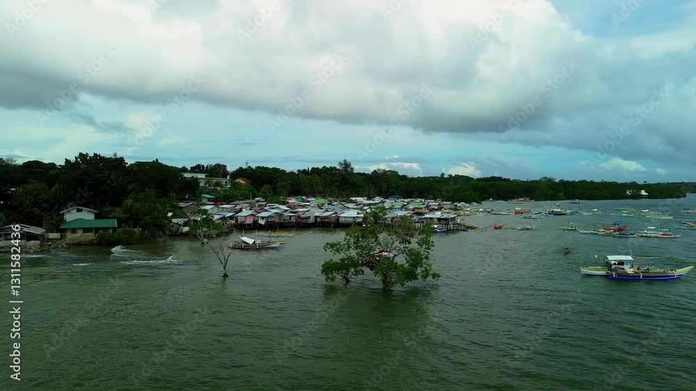 Smooth aerial shot flying backward from a unique treehouse over the sea, revealing a scenic fishermen village and traditional boats in Puerto Princesa, Palawan Island, Philippines. Smooth aerial shot flying backward from a unique treehouse over the sea, revealing a scenic fishermen village and traditional boats in Puerto Princesa, Palawan Island, Philippines.