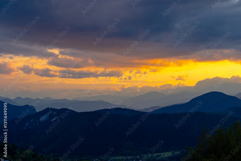 Obraz premium Silhouette of mountain range with partly cloudy sky at sunset.