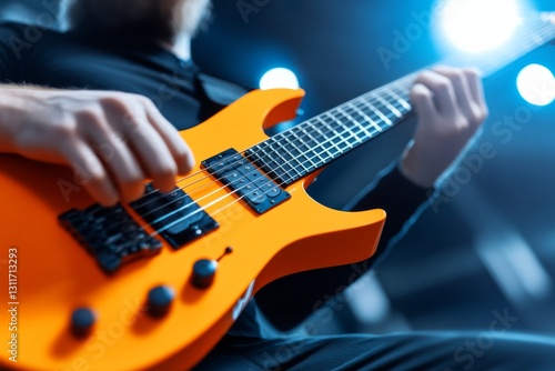 A close-up of a musician playing an orange electric guitar on stage