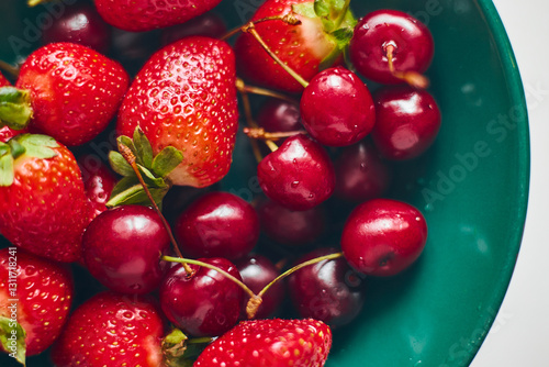 Strawberries and sweet cherries in a green plate, close-up