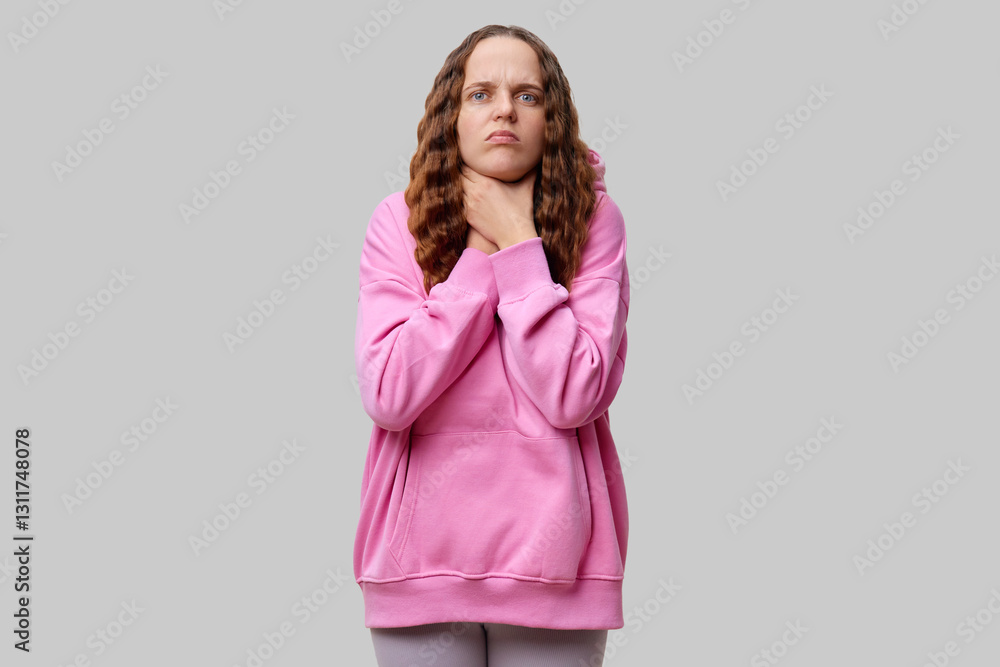 A young person stands in a relaxed pose wearing a pink hoodie, showing visible distress with hands on their neck. The background is neutral and emphasizes their expression A young person stands in a relaxed pose wearing a pink hoodie, showing visible distress with hands on their neck. The background is neutral and emphasizes their expression