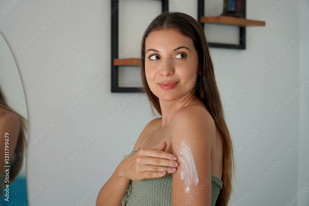 Brazilian young woman applying cream onto shoulder at home