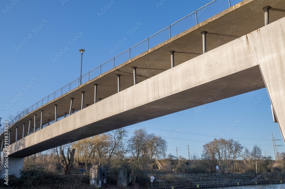 Modern concrete pedestrian bridge spanning a river in urban setting Modern concrete pedestrian bridge spanning a river in urban setting