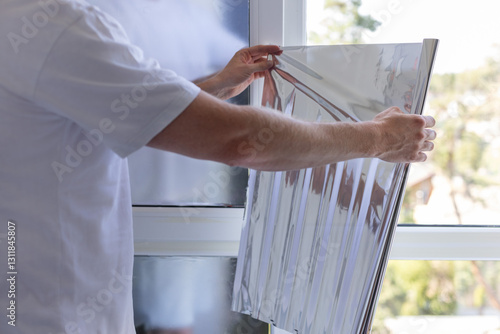 Man holding unrolled windows sun protection film.