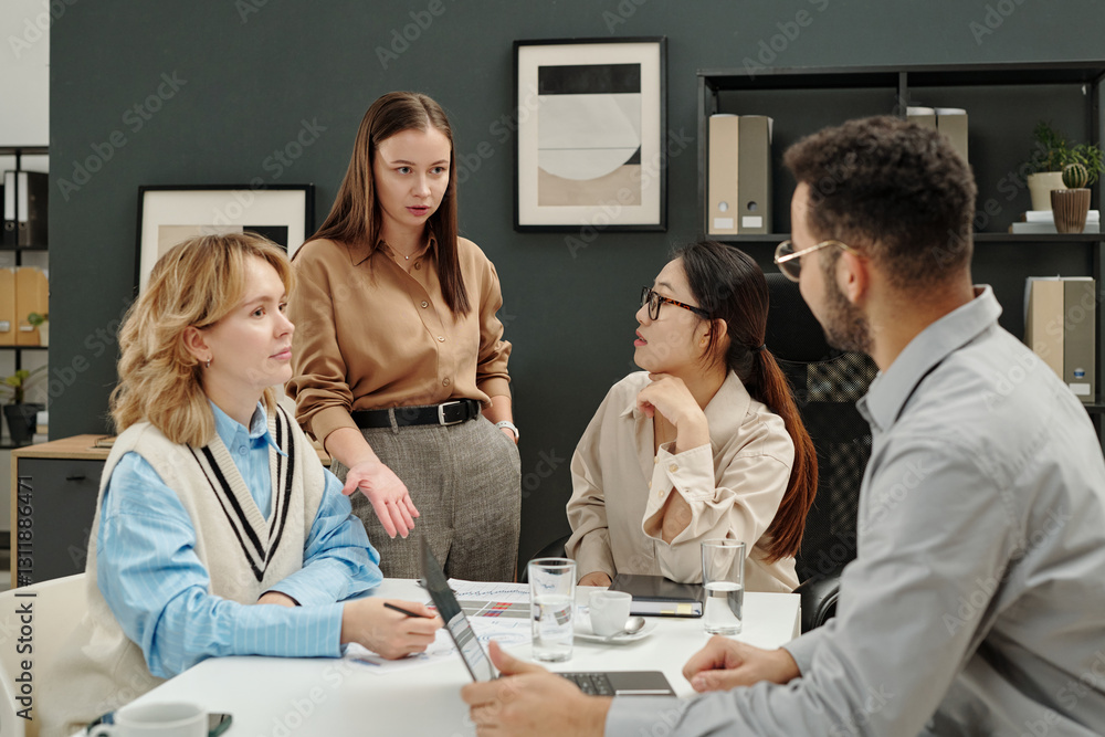 Fototapeta premium Portrait of young businesswoman as female boss talking to employees while leading business meeting with team in office 