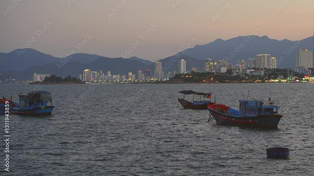 Slow panning movement of waterfront of beauty Nha Trang coastal city with wooden fishing boats on the foreground at evening time Slow panning movement of waterfront of beauty Nha Trang coastal city with wooden fishing boats on the foreground at evening time