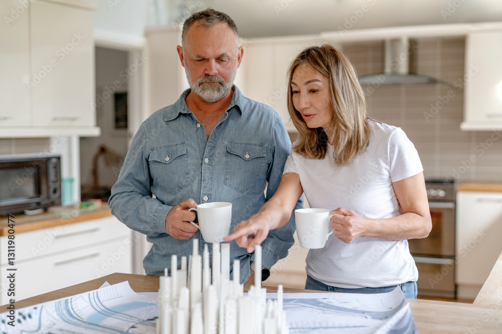 Fototapeta premium Couple discussing design project in modern kitchen while enjoying coffee in the morning light