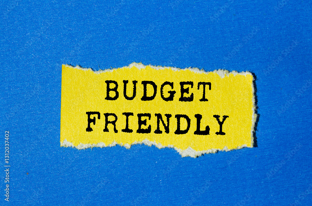 Budget friendly message written on ripped torn yellow paper on blue background. Conceptual budget friendly symbol. Copy space. Budget friendly message written on ripped torn yellow paper on blue background. Conceptual budget friendly symbol. Copy space.