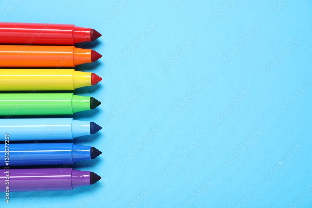 Fototapeta premium Many colorful markers on light blue background, flat lay. Space for text