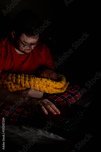 Obraz na płótnie Father Holding Baby While Using Laptop in Dim Light w salonie