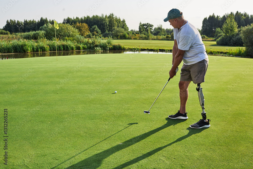 Obraz premium A passionate golfer uses a prosthetic leg to swing a putter on a lush green course under clear skies