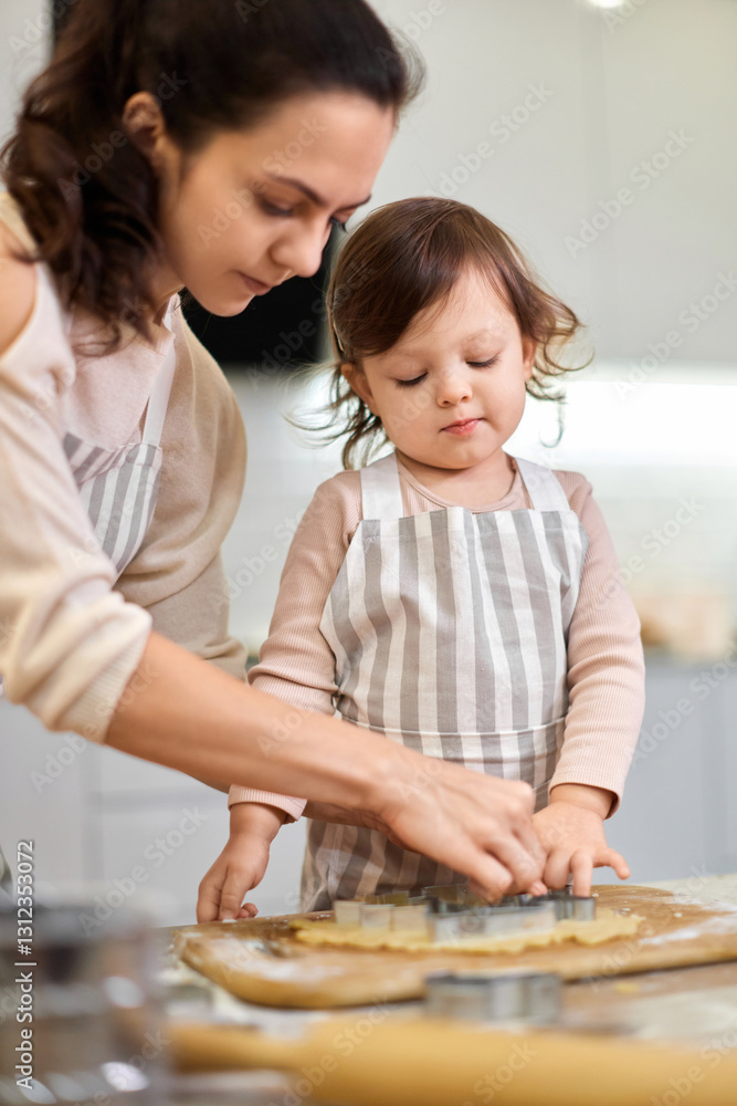 Happy family mother and little child daughter cutting cookies of raw gingerbread dough in kitchen