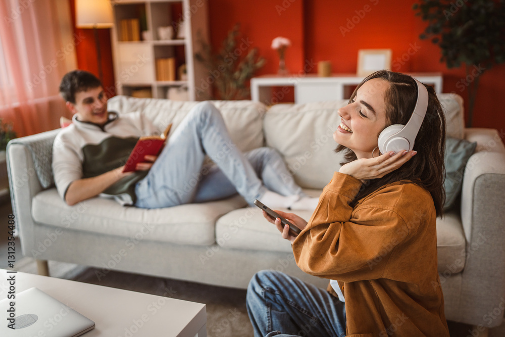Fototapeta premium happy woman with headphones listen music ad sing while man read a book
