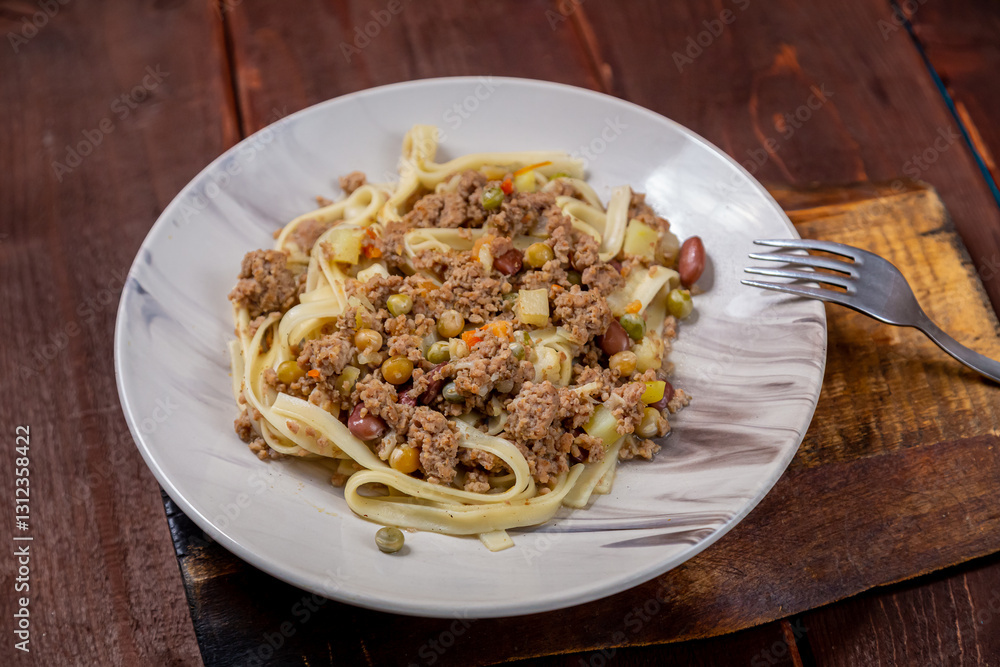 Noodles with minced meat and vegetables in sauce in a plate on the table Noodles with minced meat and vegetables in sauce in a plate on the table
