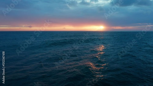 Aerial view of the beautiful landscape of Atlantic ocean while sunset, Portugal. No people. Summer.  Drone top view natural seascape with orange sun over horizon during sunset with clouds on the sky