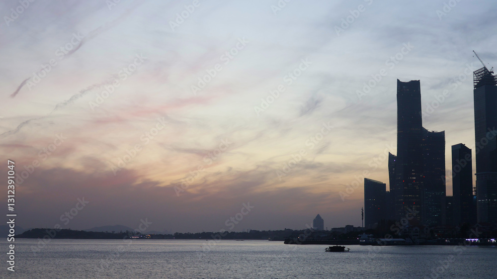 A Scenic View of the Qingdao Skyline at Dusk with Calm Waters A Scenic View of the Qingdao Skyline at Dusk with Calm Waters
