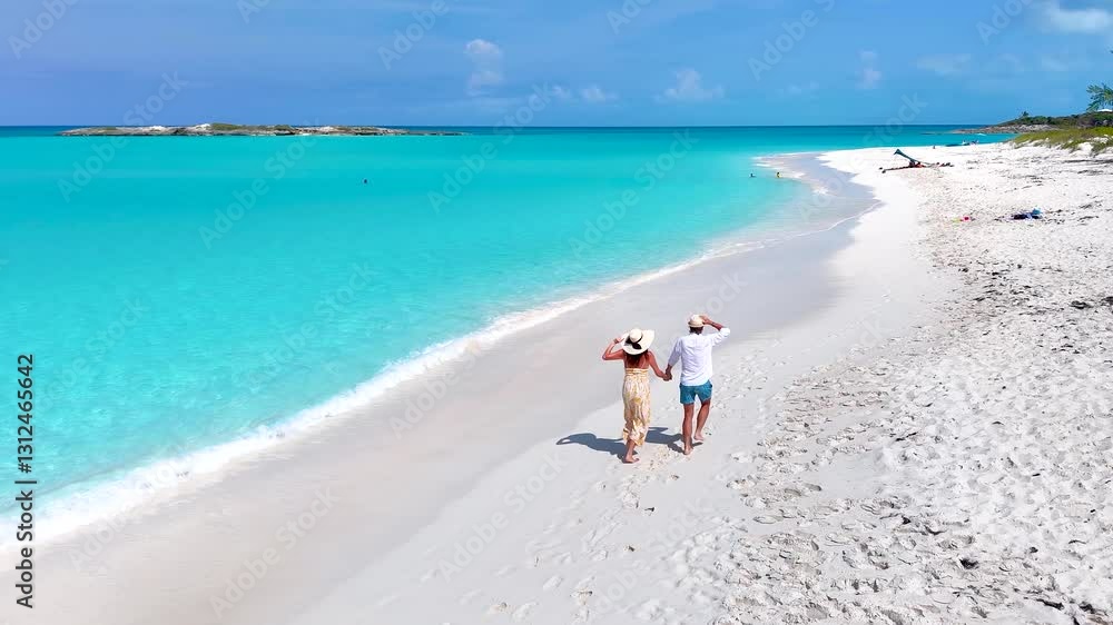 Aerial slow motion view of a happy vacation couple running on a tropical beach with turquoise ocean Aerial slow motion view of a happy vacation couple running on a tropical beach with turquoise ocean