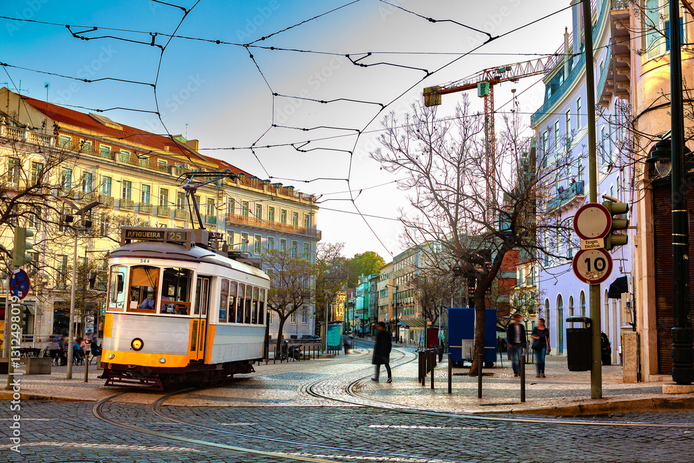 Obraz premium Tranvía tipico avanzando por calle empedrada de Lisboa, con edificios coloridos. Nostalgia y encanto: el tranvía como símbolo de la tradición y el alma vibrante de Lisboa.