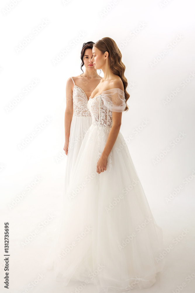 Two models in elegant bridal gowns posing together in a minimalist studio setting with soft lighting Two models in elegant bridal gowns posing together in a minimalist studio setting with soft lighting