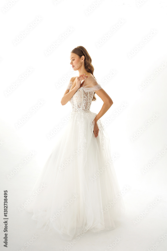 Elegant bride adjusts her wedding dress in a minimalistic setting during a bright daylight shoot Elegant bride adjusts her wedding dress in a minimalistic setting during a bright daylight shoot