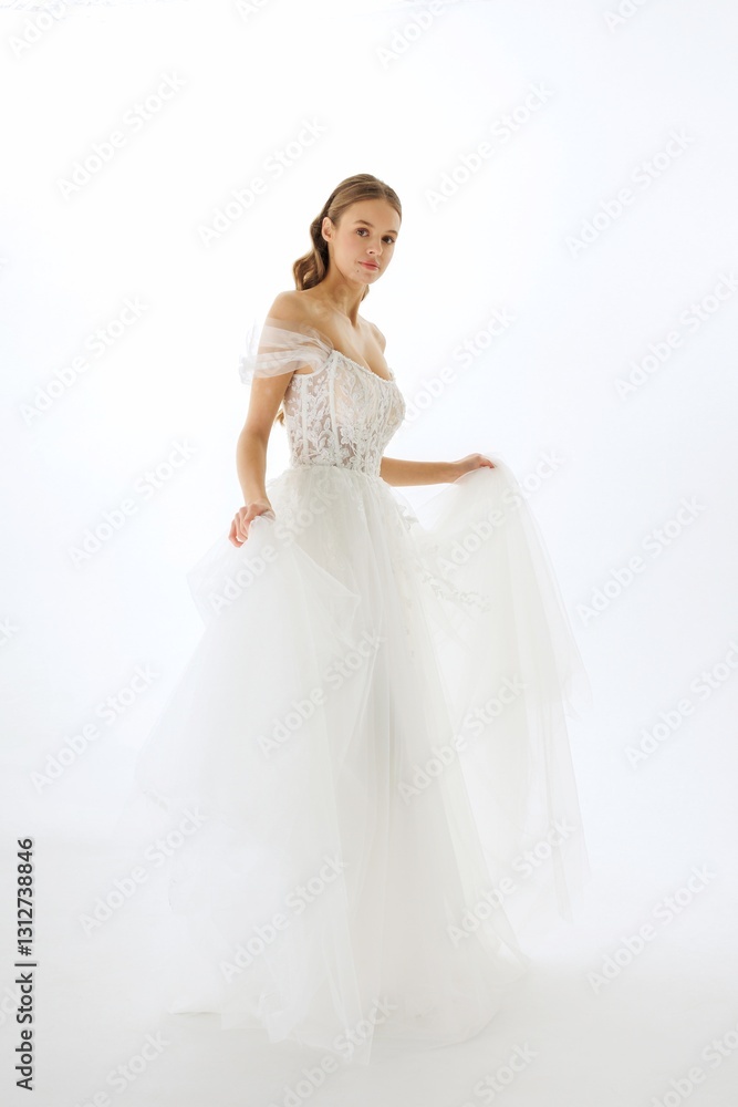 Elegant bride in white gown gracefully poses for a fashion shoot in a studio setting Elegant bride in white gown gracefully poses for a fashion shoot in a studio setting