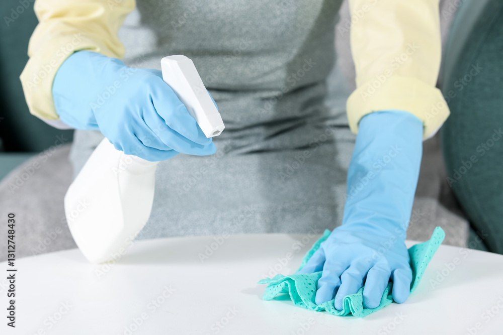 Woman using cleaning product while wiping table with rag indoors, closeup Woman using cleaning product while wiping table with rag indoors, closeup