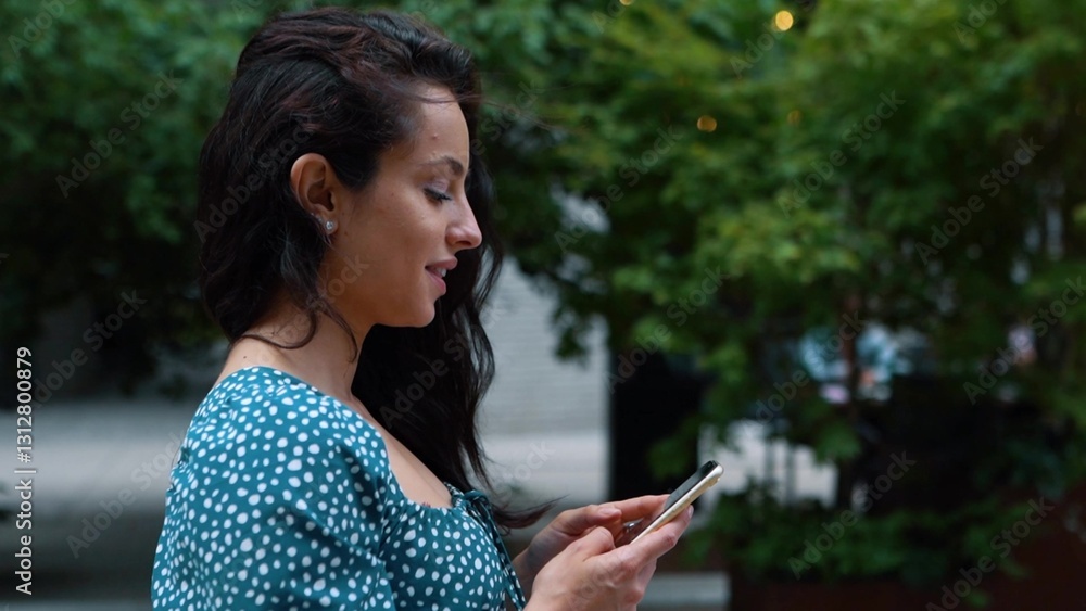 Young beautiful attractive woman texting message on smartphone on social media while walking in town outdoors. Close up. Side view. Pretty happy brunette female browsing online on cellphone outdoor. Young beautiful attractive woman texting message on smartphone on social media while walking in town outdoors. Close up. Side view. Pretty happy brunette female browsing online on cellphone outdoor.