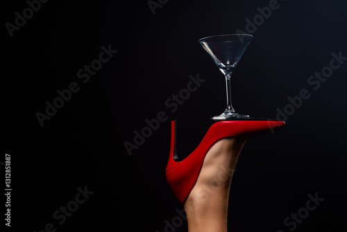 Elegant balancing act showcasing red high heel and martini glass against dark background