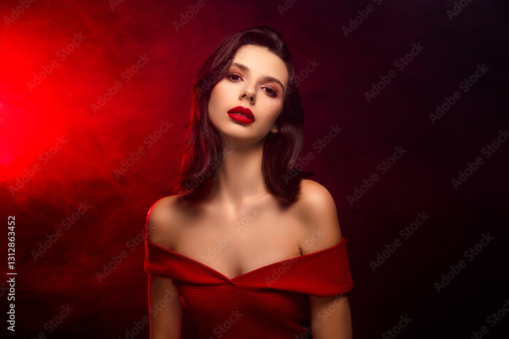 Elegant young woman in red dress with dramatic lighting and styled hair on dark background Elegant young woman in red dress with dramatic lighting and styled hair on dark background