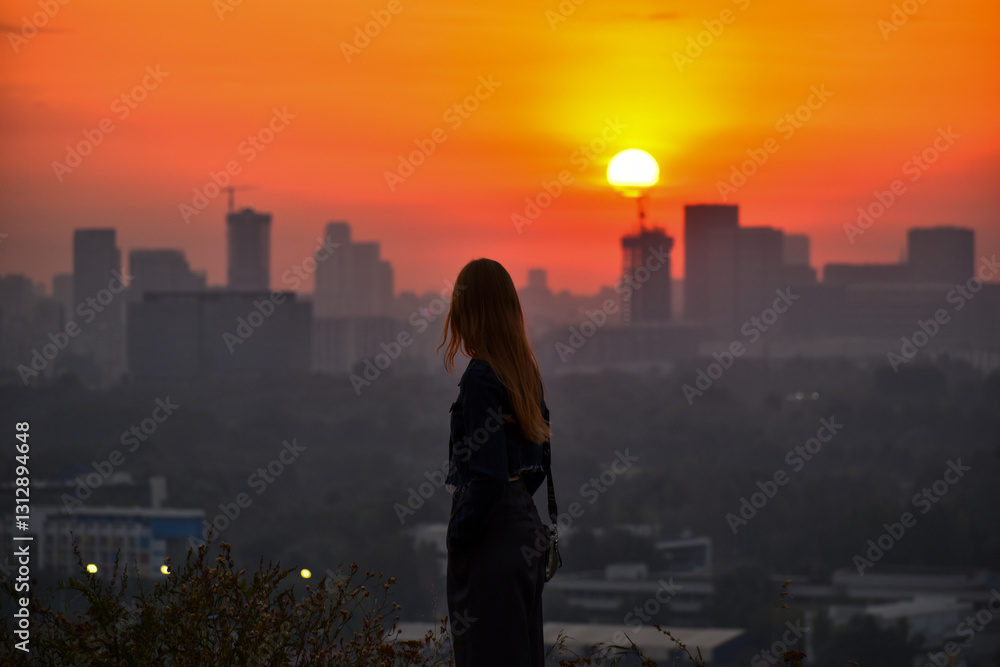 Fototapeta premium Young woman Watching Sunset Over the City Skyline