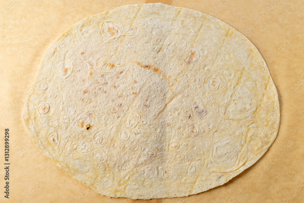 Handmade tortilla on parchment paper ready for filling Handmade tortilla on parchment paper ready for filling