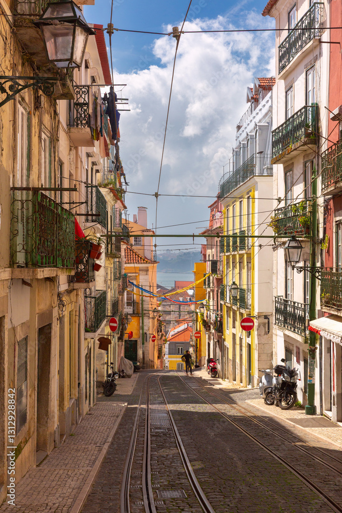 A steep cobbled street with tram tracks in the Bica district of Lisbon, Portugal